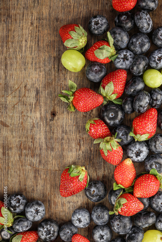 Fresh ripe Blueberry strawberry grape macro closeup on wood dark white background