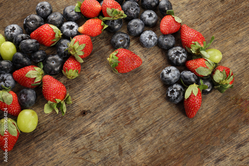 Fresh ripe Blueberry strawberry grape macro closeup on wood dark white background
