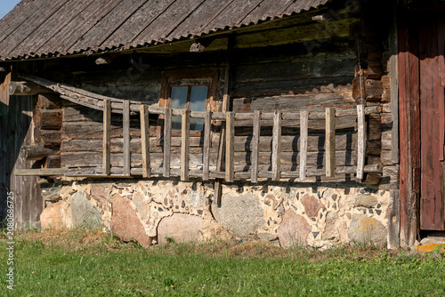 Traditional old wooden farmhouse in rural Lithuania featuring a log structure, stone foundation, weathered timber walls, and authentic Baltic countryside architecture