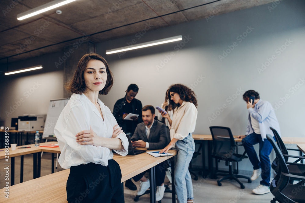 Naklejka premium Confident female leader standing in modern office with diverse team working