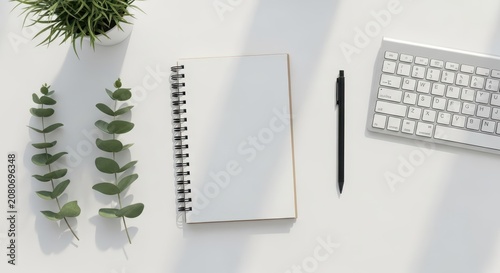 Clean white office workspace flatlay with open spiral notebook, black pen, and keyboard