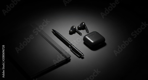 Sleek wireless earbuds and a modern pen rest on a dark notebook surface, showcasing essential modern technology for work and creativity.