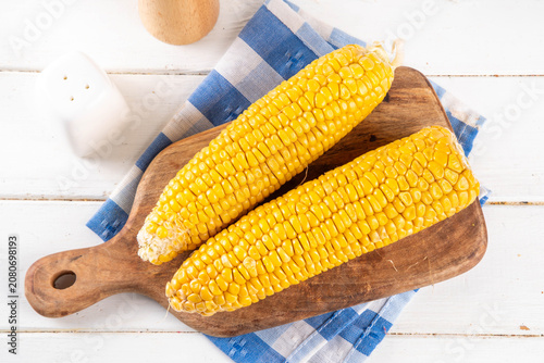 Photos Sweet boiled corn cobs portions on plate, with salt and spices