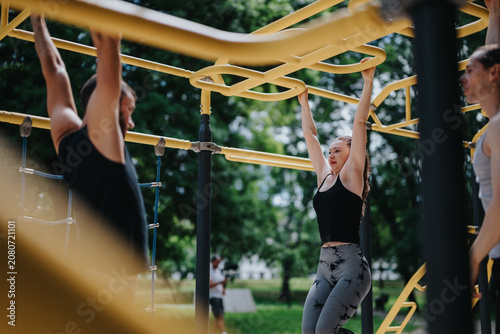 Photography A young woman performs a monkey bar exercise on yellow outdoor fitness equipment