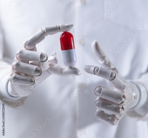 Robot doctor hand holding a red and white capsule pill close up.