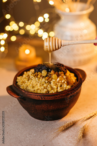 Traditional Ukrainian Christmas dish Kutia made of wheat berries, poppy seeds, and raisins served in a clay bowl with a wooden spoon
