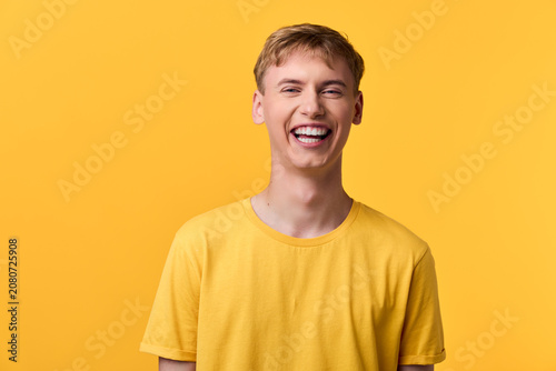 Fotografie Cheerful man wearing a yellow tee smiles against a bright yellow backdrop, conve
