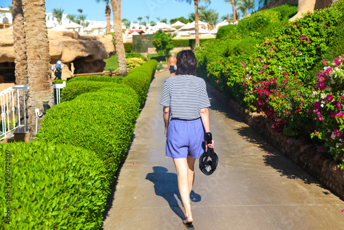 woman returns from the beach, carrying a snorkeling mask in her hand, embodying the spirit of summer adventures and ocean exploration.
