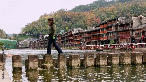 Female tourist walking on stepping stones in Fenghuang Ancient Town, China