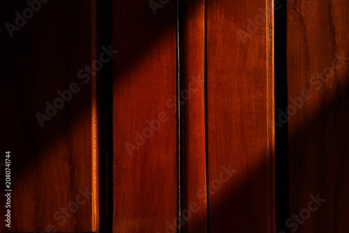 A close-up shot of a rich, reddish-brown wooden surface, possibly a door or paneling.
