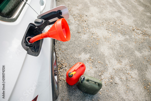 Open vehicle fuel filler with fuel containers ready for refueling outdoors. Concept: emergency fuel reserve
