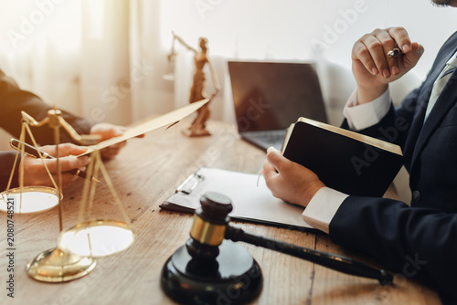 The lawyer sat in front of a laptop in a room filled with documents and smartphones, with a hammer and scales beside him, advising his female client on matters of justice and legal principles.