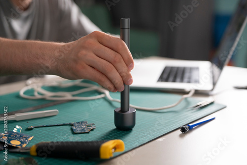 Foto A hand adjusts a tool while standing at a worktable surrounded by electronic par