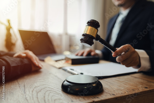 The lawyer sat in front of a laptop in a room filled with documents and smartphones, with a hammer and scales beside him, advising his female client on matters of justice and legal principles.