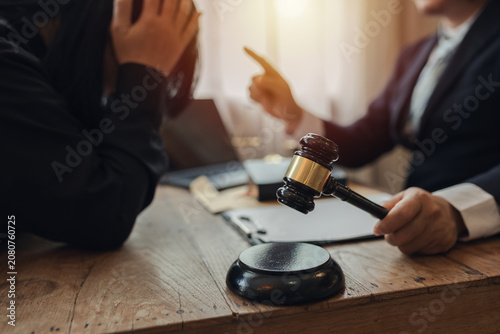The lawyer sat in front of a laptop in a room filled with documents and smartphones, with a hammer and scales beside him, advising his female client on matters of justice and legal principles.