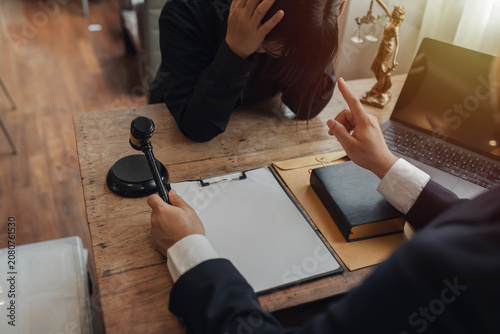 The lawyer sat in front of a laptop in a room filled with documents and smartphones, with a hammer and scales beside him, advising his female client on matters of justice and legal principles.