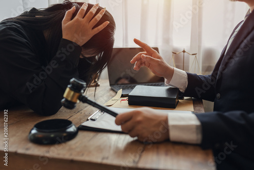 The lawyer sat in front of a laptop in a room filled with documents and smartphones, with a hammer and scales beside him, advising his female client on matters of justice and legal principles.