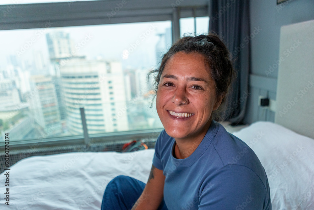 Fototapeta premium Woman smiling relaxing on bed in hotel room