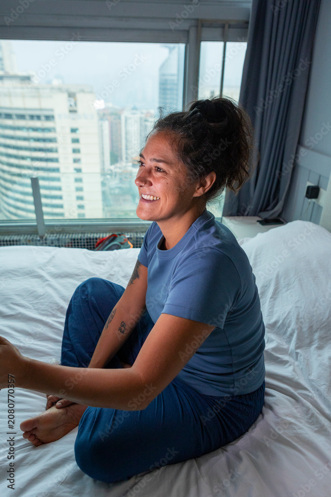 Fototapeta premium Woman relaxing in bed enjoying hotel room view