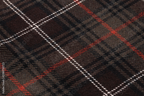 Dark Brown Tartan Plaid Wool Fabric Texture Close-Up Macro with Red and White Checkered Pattern Background
