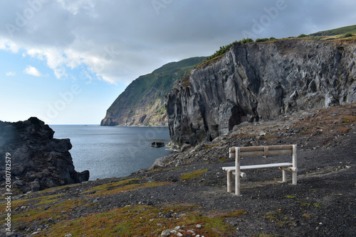 Canvastavla A wooden bench overlooking a dramatic volcanic coastline and vast ocean under a