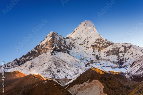 Snowy mount Ama Dablam illuminated by rising sun. Sunrise iew from Pangboche village on Everest base camp trek in Nepal.