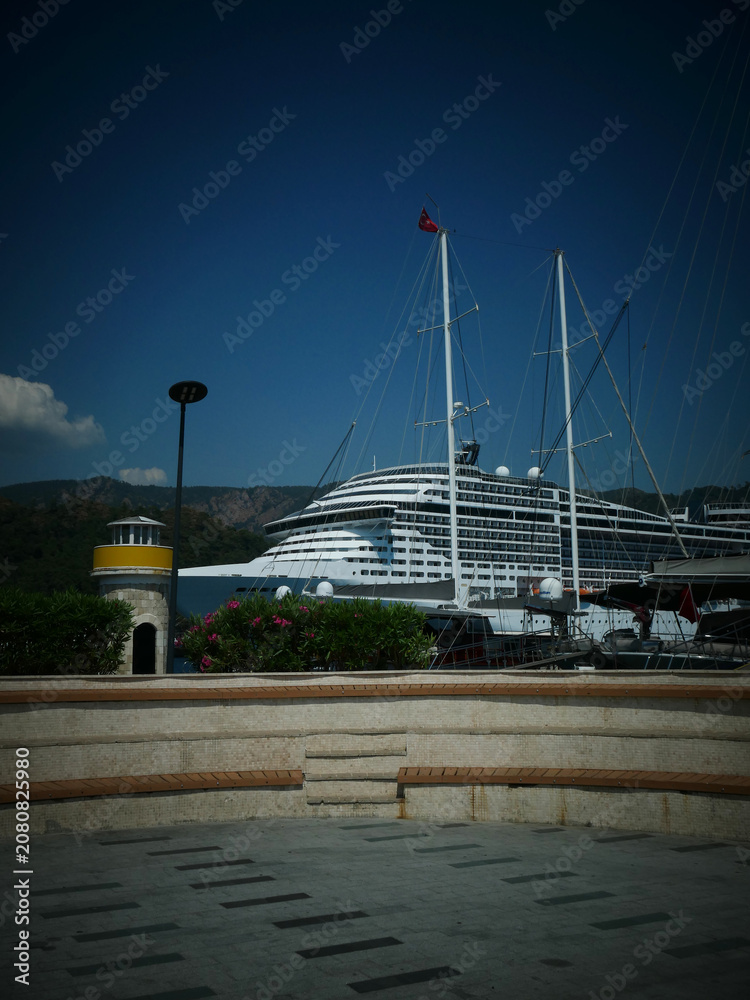 Fototapeta premium Large cruise ship docked at a harbor with small lighthouse