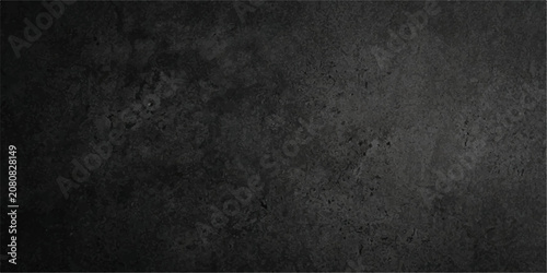 Deep black speckled concrete abstract background, dark charcoal concrete with fine speckled grain and soft light centre, elegant backdrop for wallpaper, packaging and branding.