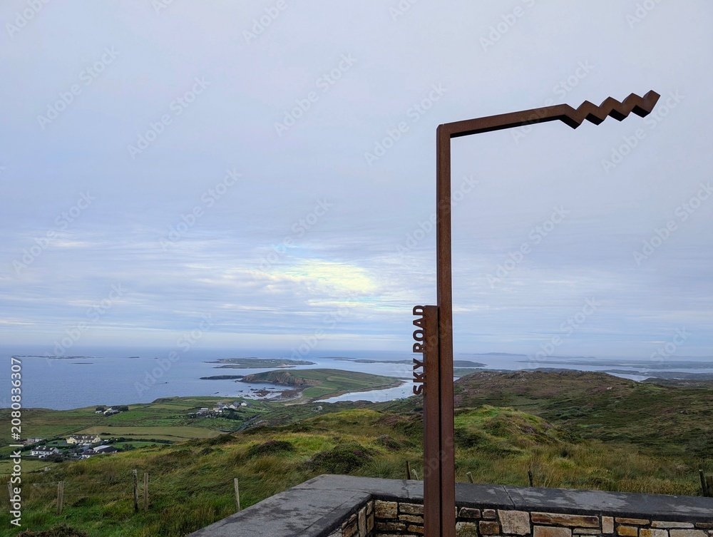 Fototapeta premium The iconic rusty metal Sky Road sign overlooking the spectacular coastal landscape and islands in Connemara, County Galway, Ireland.