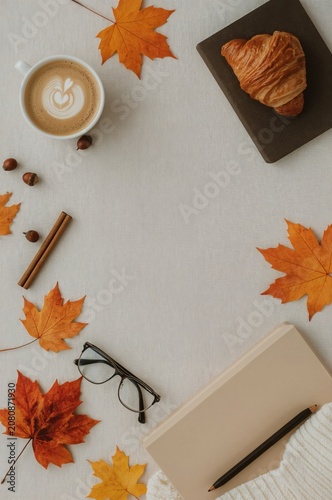 Cozy Autumn Scene With Coffee, Croissant, and Fallen Leaves on a Table