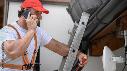  Working at heights. Electrician during adjustment of directional WiFi antenna.