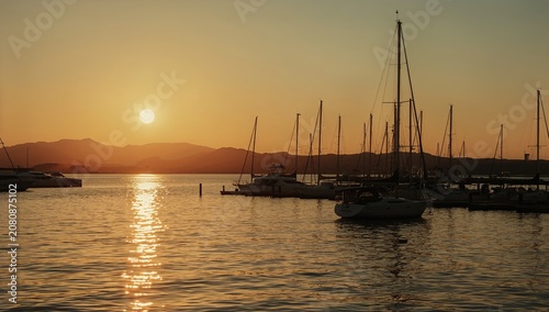 Sunset Over a Marina With Boats and Mountains in the Background