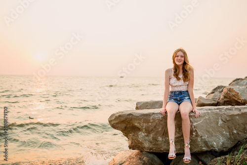 Girl sitting on rocks by lake