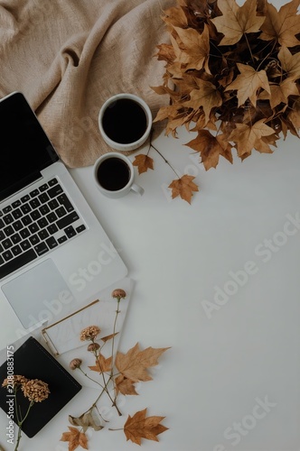 Cozy Workspace With Laptop, Coffee Cups, and Autumn Leaves in a Warm Setting