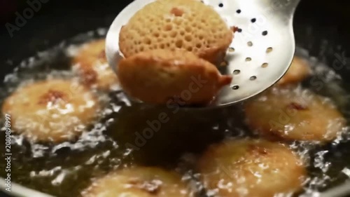 Static Shot Of Akara Fried Bean Cakes Being Lifted Out Of Golden Oil With A Perforated Spatula Showcasing Their Crispy Texture And Bubbling Fry Process