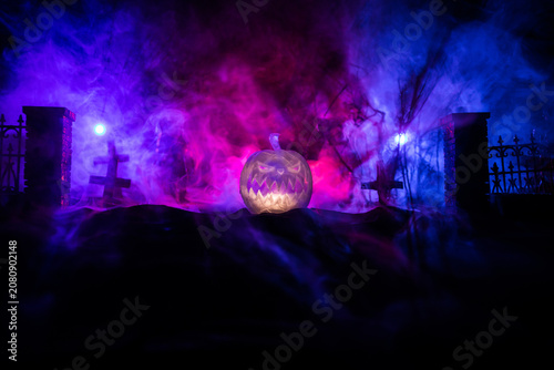 Halloween concept. Creepy silhouette in the dark corridor with pumpkin head. Toned light with fog on background.