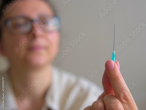 фотографія woman holding a sharp hypodermic needle for an injection before a vaccination, t