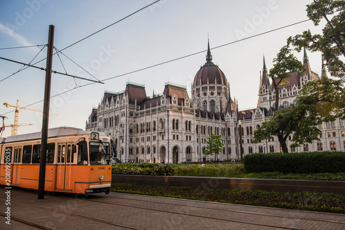 Canvas Print Iconic yellow tram moving past the Hungarian Parliament Building in Budapest during golden hour