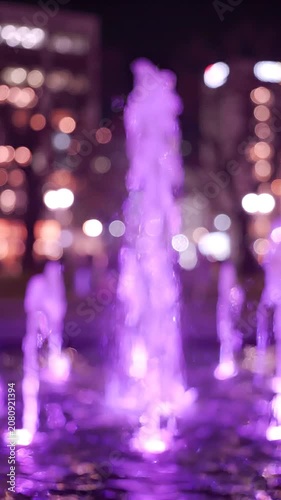 Captivating Purple Water Fountain Illuminated at Night, Creating a Magical Atmosphere with Its Luscious Streams and Vibrant Colors, Enhancing the Urban Landscape