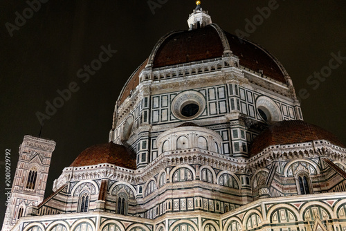 The iconic Duomo and its bell tower stand majestically against the dark night sky, showcasing intricate Renaissance architecture
