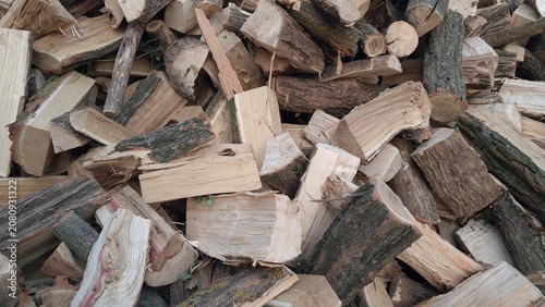 Pile of chopped firewood logs as natural wooden background texture