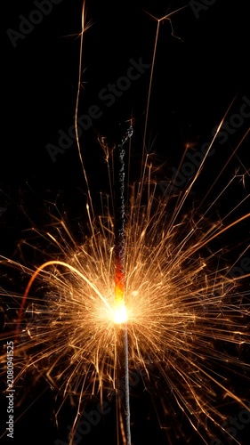 Burning Sparkler with Golden Sparks on Black Background

