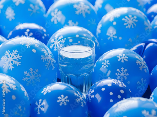 Glass of Water Surrounded by Blue Winter Balloons With Snowflakes