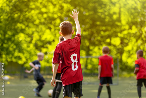Foto Young Football Player Raising Hand: Boy in Red Jersey Number 8 from Back View on