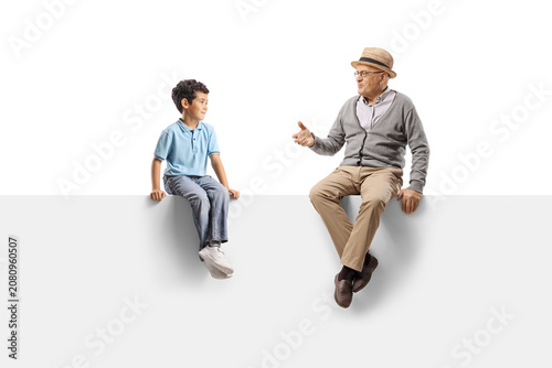 Grandfather and grandson sitting on a white panel and talking to each other