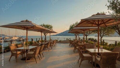 Dining Area Near the Water With Tables, Chairs, and Umbrellas at Sunset in a ...