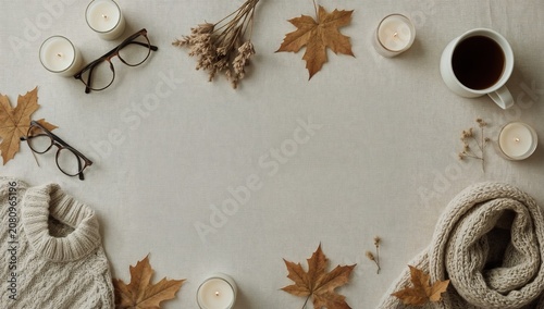 Cozy Setup With Leaves, Candles, a Mug, and Warm Clothing on a Table