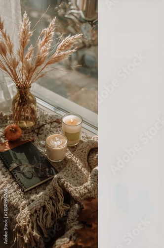Cozy Indoor Space With Candles, a Notebook, and Dried Plants Near a Window on...