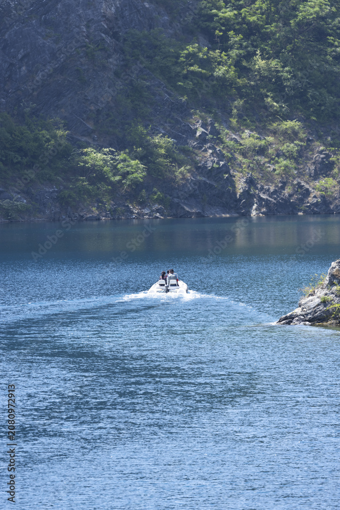 Fototapeta premium Motorboat with Two People on a Mountain Lake