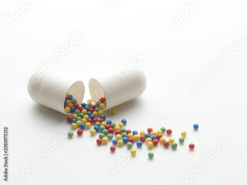 Open Medicine Capsule with Colorful Microgranules on White Background